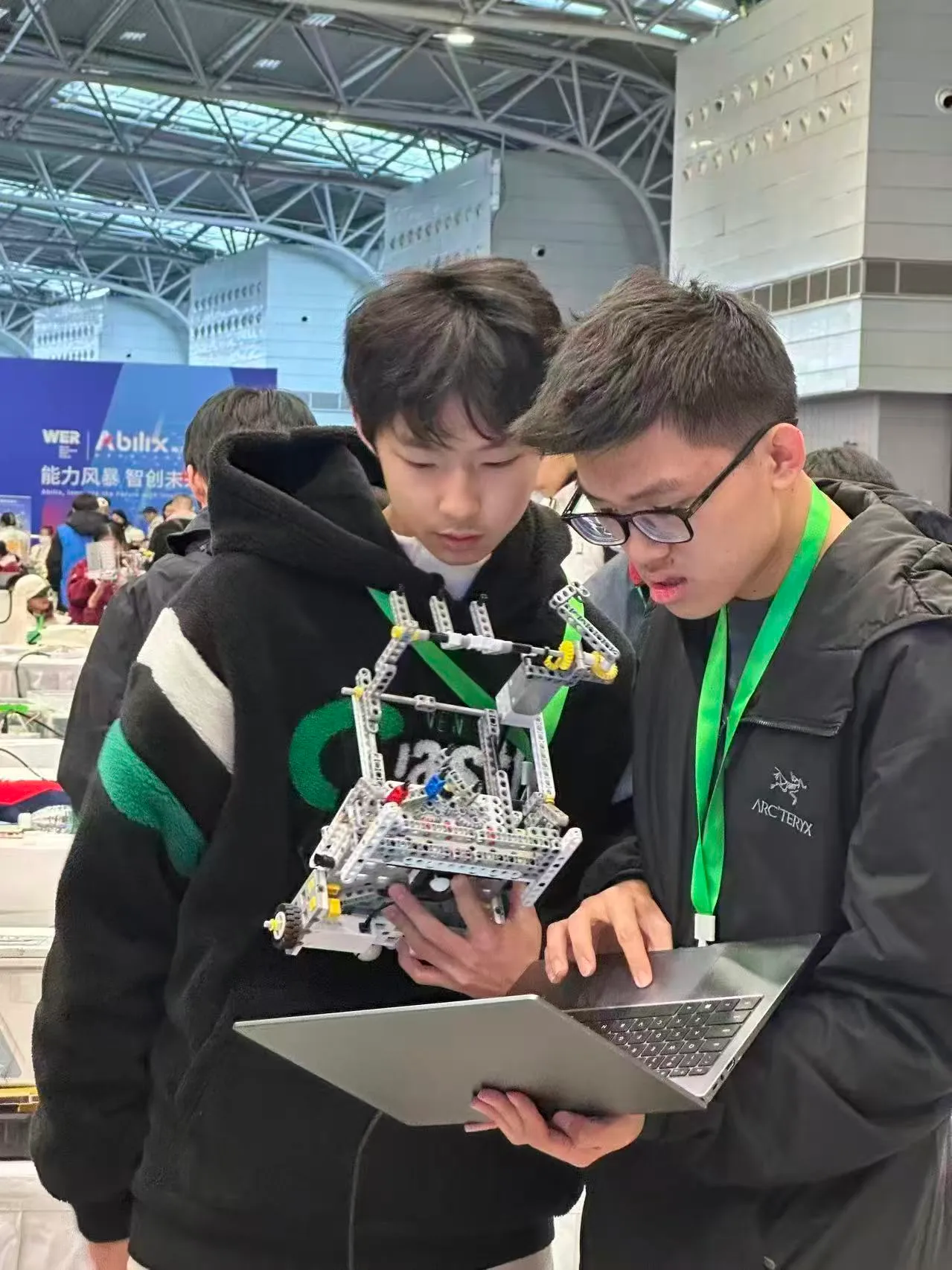 Noah and a teammate debugging a competition robot beside a laptop